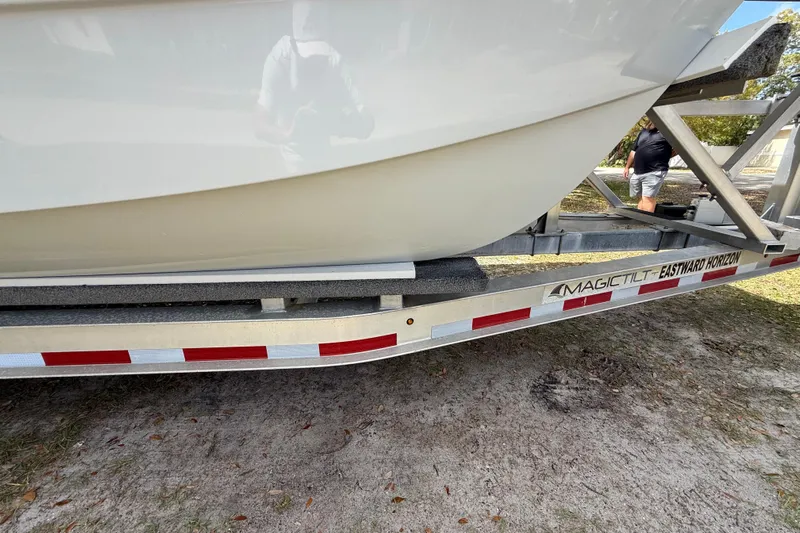  Yacht Photos Pics Trailer carrying 2022 Eastward 30 boat, Magic Tilt brand, on grassy ground.