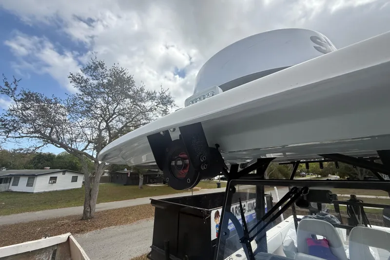  Yacht Photos Pics 2022 Eastward 30 boat with radar, parked near trees and houses under cloudy sky.
