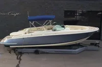 2024 Chris-Craft Launch 28 GT boat with blue canopy on trailer.