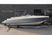 2024 Chris-Craft Launch 28 GT boat with blue canopy on trailer, side view.