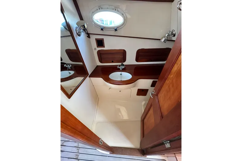 Lida Yacht Photos Pics Hinckley Picnic Boat 36 bathroom interior, featuring wood accents and a round porthole window.