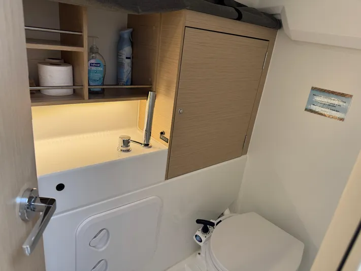 Stinger Yacht Photos Pics Beneteau Oceanis 30.1 2022 yacht bathroom with sink, toilet, and storage shelves.