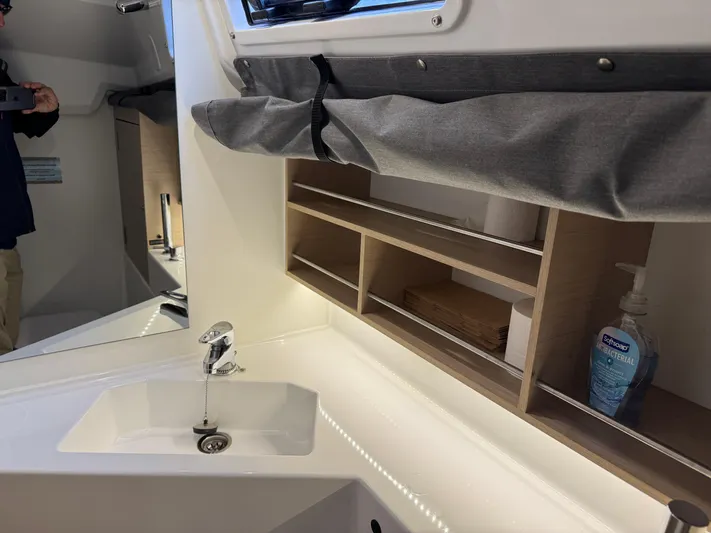 Stinger Yacht Photos Pics Modern bathroom interior of 2022 Beneteau Oceanis 30.1 yacht with sink and storage shelves.