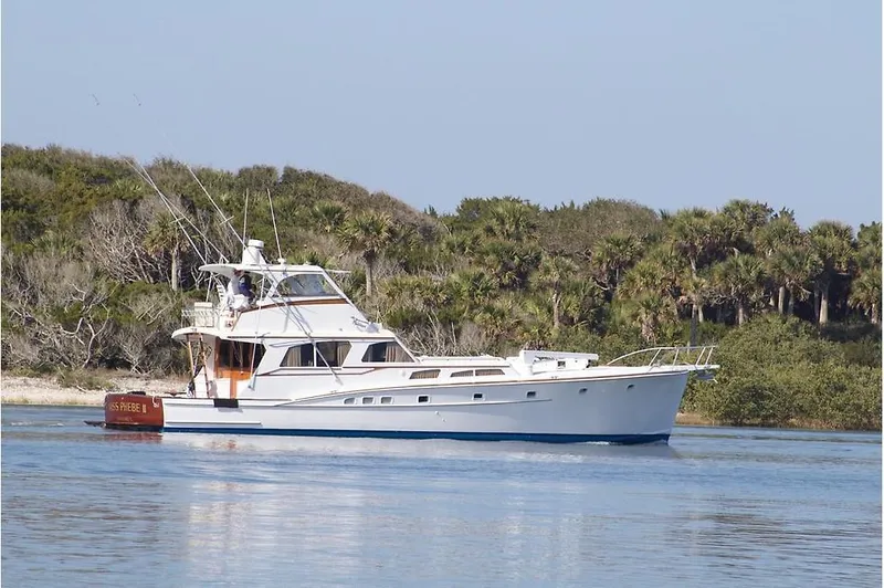 Miss Phebe II Yacht Photos Pics 1971 Whiticar Sportfish yacht cruising near a lush, tree-lined shoreline.