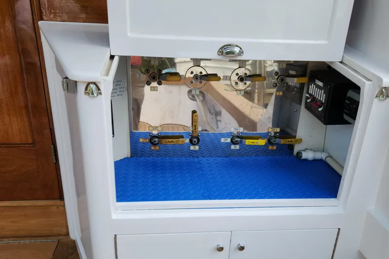 Miss Phebe II Yacht Photos Pics 1971 Whiticar Sportfish control panel with valves and switches in a white cabinet.