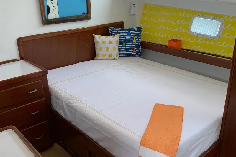 Miss Phebe II Yacht Photos Pics 1971 Whiticar Sportfish cabin with bed, colorful pillows, and wooden furniture.