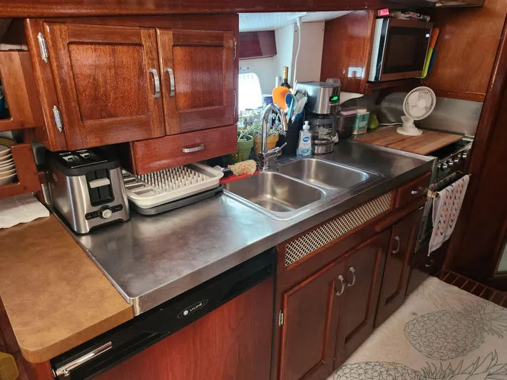 Miss Phebe II Yacht Photos Pics 1971 Whiticar Sportfish kitchen with wooden cabinets, stainless steel sink, and modern appliances.