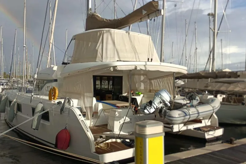  Yacht Photos Pics 2021 Lagoon 50 catamaran docked at marina with inflatable boat and rainbow in background.