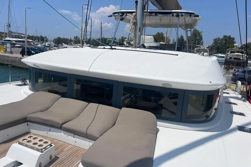  Yacht Photos Pics 2021 Lagoon 50 yacht with cushioned deck, docked at marina under clear sky.