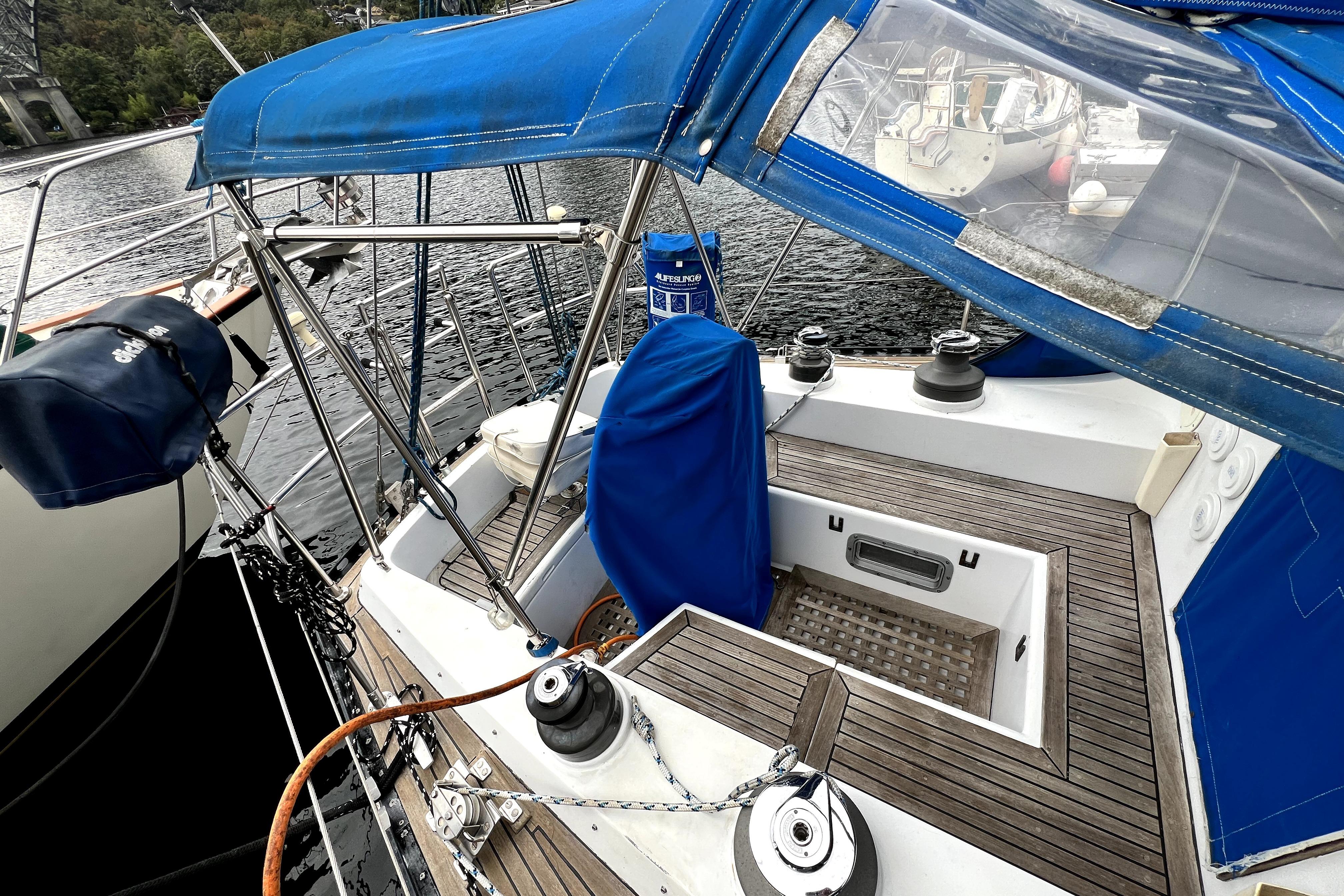 1983 CT 38 Warwick sailboat cockpit with blue canopy and wooden deck, docked by the water.