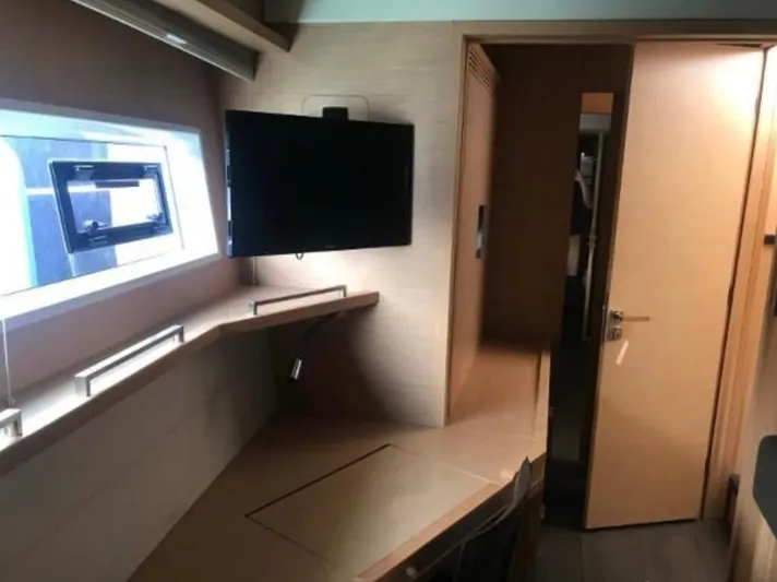 Sunset O Yacht Photos Pics Luxurious interior of 2019 Lagoon 620 yacht with desk, TV, and window.