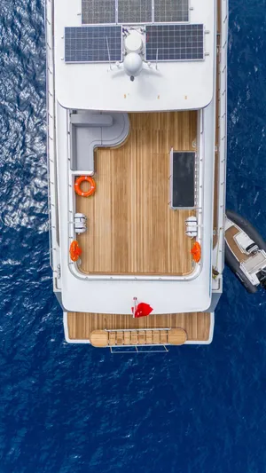  Yacht Photos Pics Aerial view of 2024 Custom 27m Trawler with solar panels and wooden deck on blue ocean.