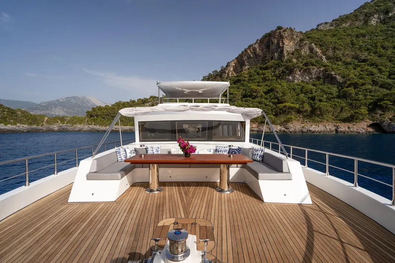  Yacht Photos Pics Luxurious 2024 Custom 27m Trawler with spacious deck, scenic coastal backdrop, and elegant seating area.