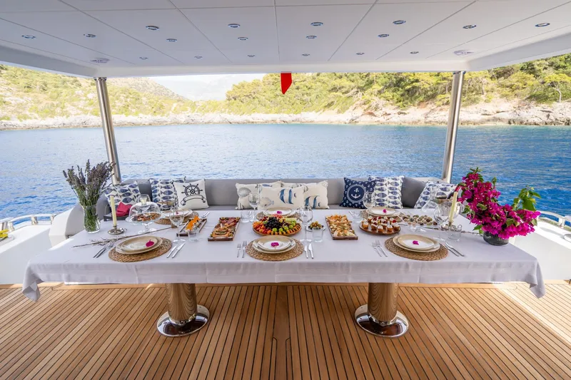  Yacht Photos Pics Luxurious dining setup on 2024 Custom 27m Trawler yacht, overlooking serene waters and lush greenery.