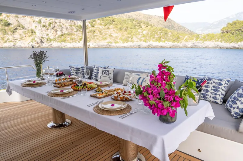  Yacht Photos Pics Elegant dining setup on 2024 Custom 27m Trawler, featuring floral centerpiece and scenic ocean view.