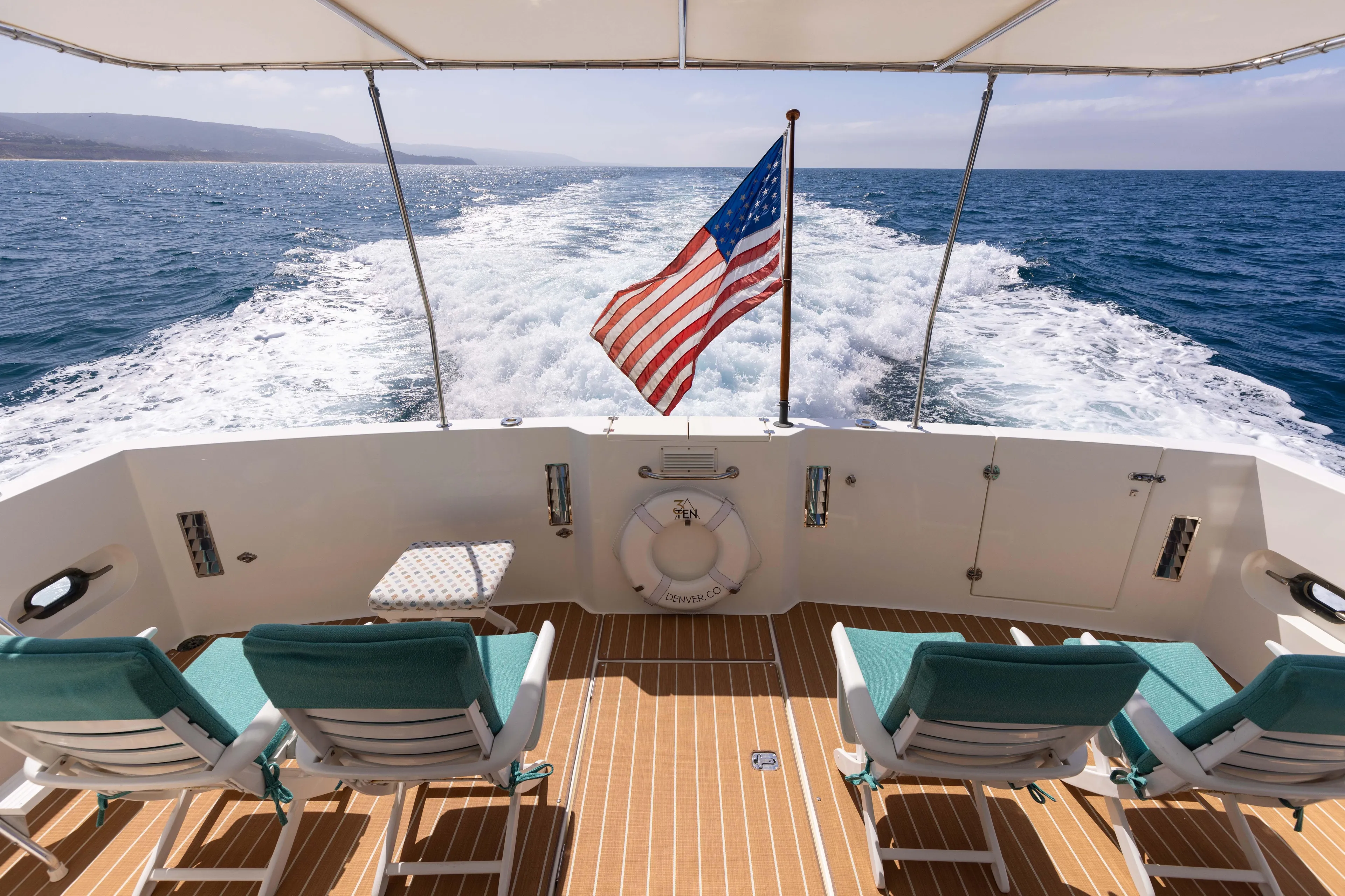3ten Yacht Photos Pics 1997 West Bay Sonship yacht deck with chairs, American flag, ocean view.
