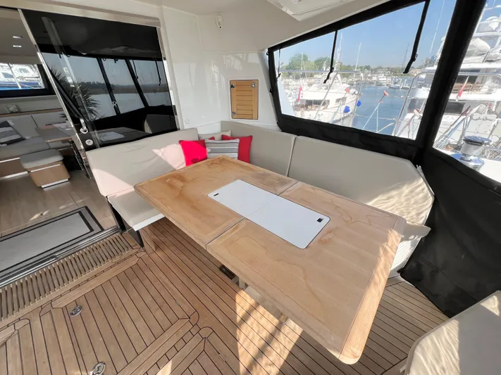 Rogue Yacht Photos Pics Luxurious Privilege 510 yacht interior with wooden table, cushioned seating, and marina view.