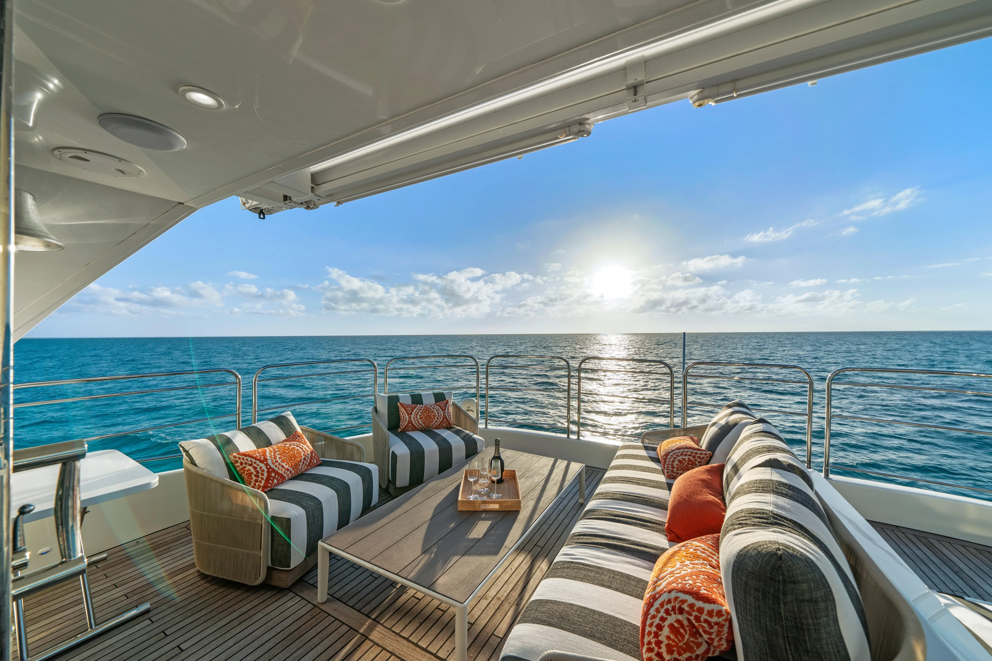 Royal Rita Yacht Photos Pics Luxurious Sunreef 70 yacht deck with ocean view, striped seating, and sunset ambiance.