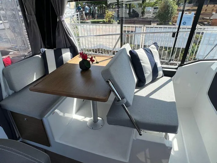  Yacht Photos Pics Interior seating area of 2021 Jeanneau 895 boat with table and striped cushions.