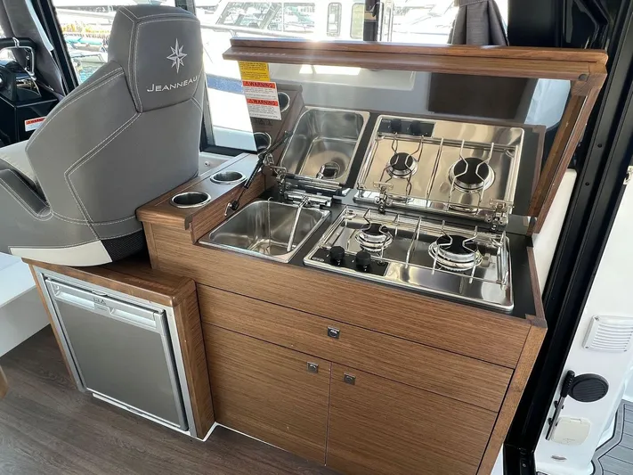  Yacht Photos Pics 2021 Jeanneau 895 boat interior kitchen with stove, sink, and refrigerator.