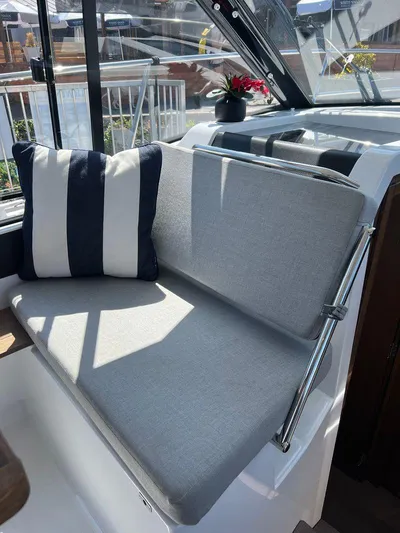  Yacht Photos Pics 2021 Jeanneau 895 boat interior with cushioned seating and striped pillow.