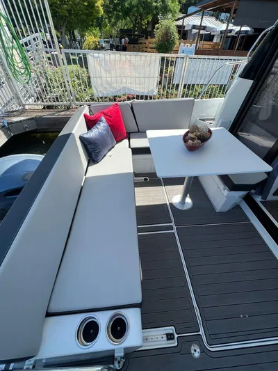  Yacht Photos Pics Outdoor seating area on a 2021 Jeanneau 895 boat with cushions and table.