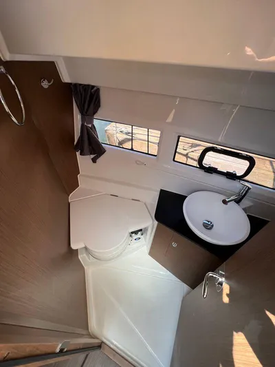  Yacht Photos Pics Compact bathroom in 2021 Jeanneau 895 boat with sink, toilet, and window.