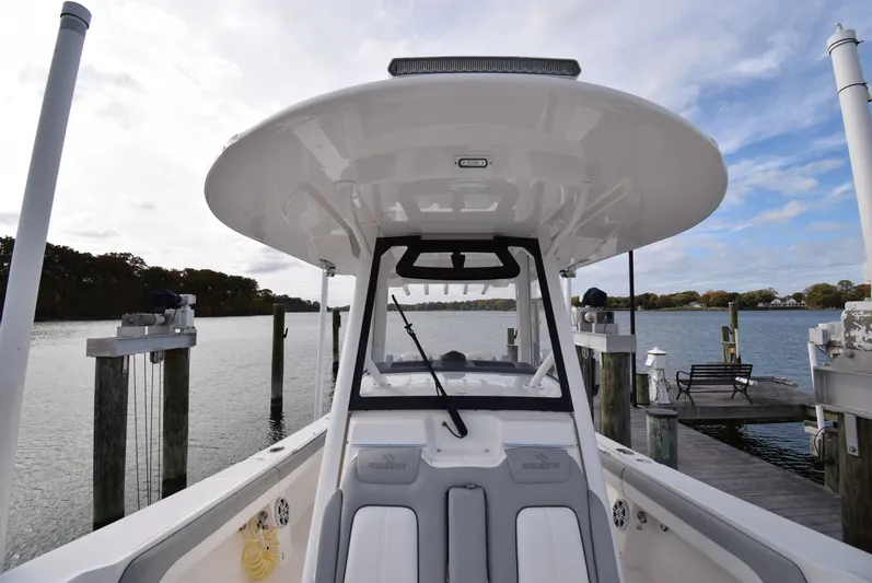 Shore Runner Yacht Photos Pics 2021 Regulator 34 boat docked by a serene waterfront with clear skies.