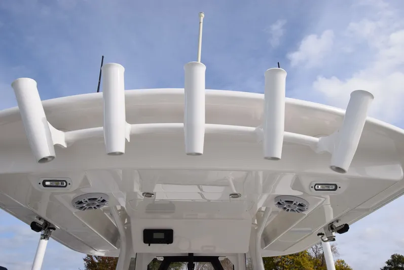 Shore Runner Yacht Photos Pics 2021 Regulator 34 boat roof with rod holders and speakers against a cloudy sky.