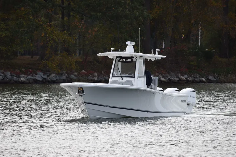 Shore Runner Yacht Photos Pics 2021 Regulator 34 boat cruising on a calm lake with wooded shoreline.