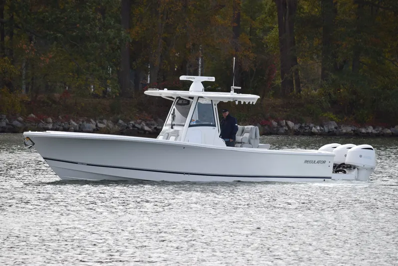 Shore Runner Yacht Photos Pics 2021 Regulator 34 boat cruising on a calm lake with wooded shoreline.