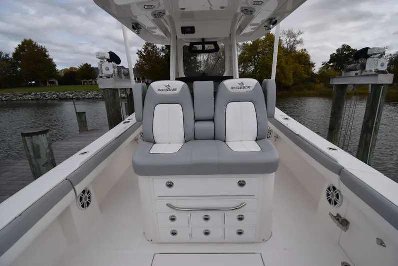 Shore Runner Yacht Photos Pics 2021 Regulator 34 boat interior with dual seats and storage, docked by a scenic waterfront.