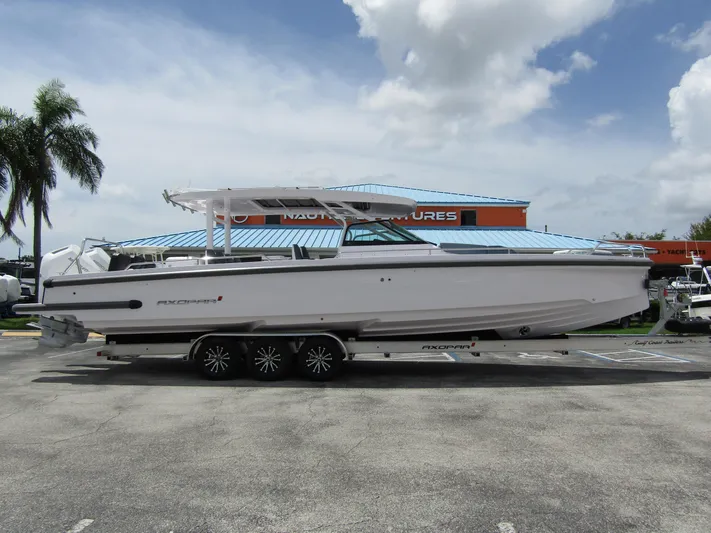  Yacht Photos Pics 2024 Axopar 37 Sun Top boat on trailer, parked outdoors under cloudy sky.