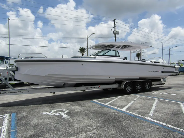  Yacht Photos Pics 2024 Axopar 37 Sun Top boat on trailer under cloudy sky.