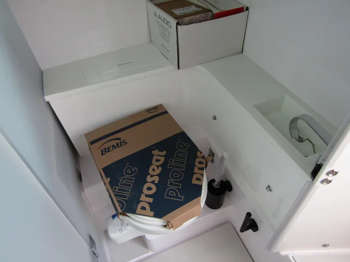  Yacht Photos Pics 2024 Axopar 37 Sun Top storage area with boxes and plumbing fixtures.