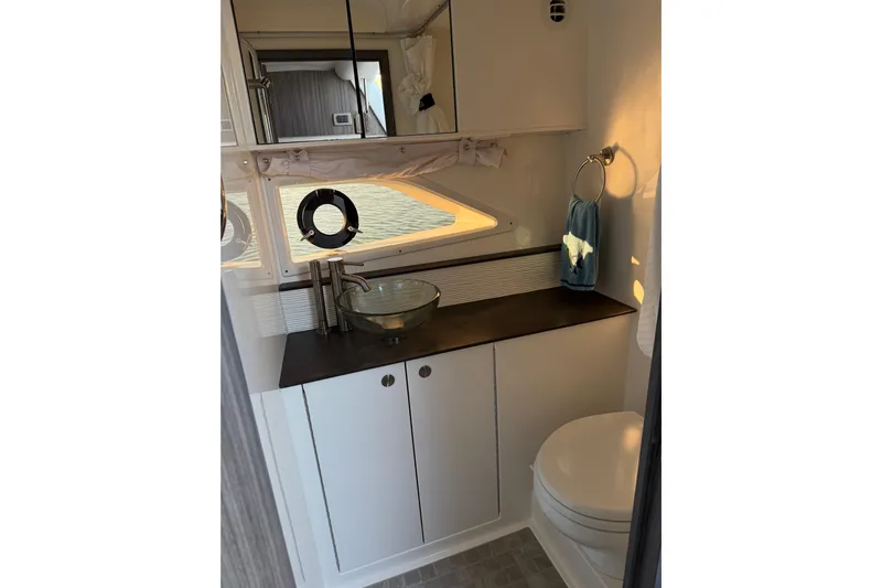  Yacht Photos Pics 2020 Sea Ray Sundancer 320 bathroom with modern sink, mirror, and porthole window.