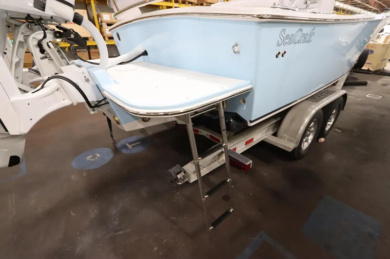  Yacht Photos Pics 2024 SeaCraft 23CC boat on trailer, featuring a swim platform and ladder.