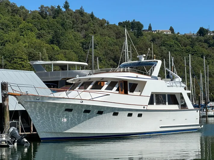  Yacht Photos Pics 1985 Ocean Alexander Pilothouse yacht docked in a marina, surrounded by lush greenery.