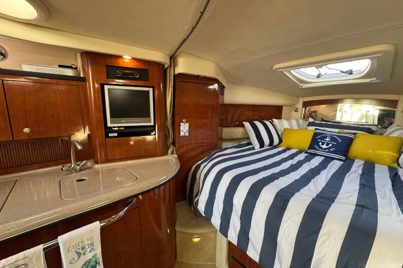  Yacht Photos Pics Interior of 2007 Sea Ray 340 Sundancer with cozy bed, striped bedding, and compact kitchenette.