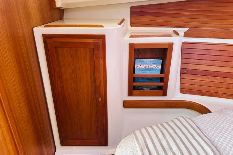 Watermark Yacht Photos Pics 2017 Back Cove 32 cabin interior with wooden cabinetry and a book on Maine Coast cruising.