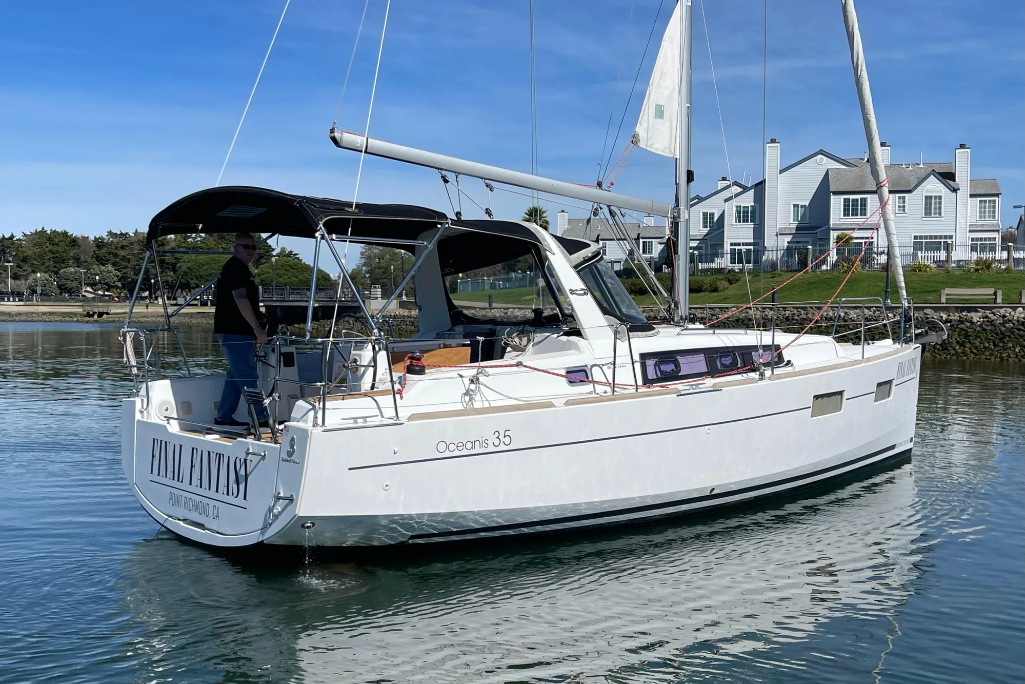 A Beneteau Oceanis 35 sailboat named "Final Fantasy" on calm water near houses.