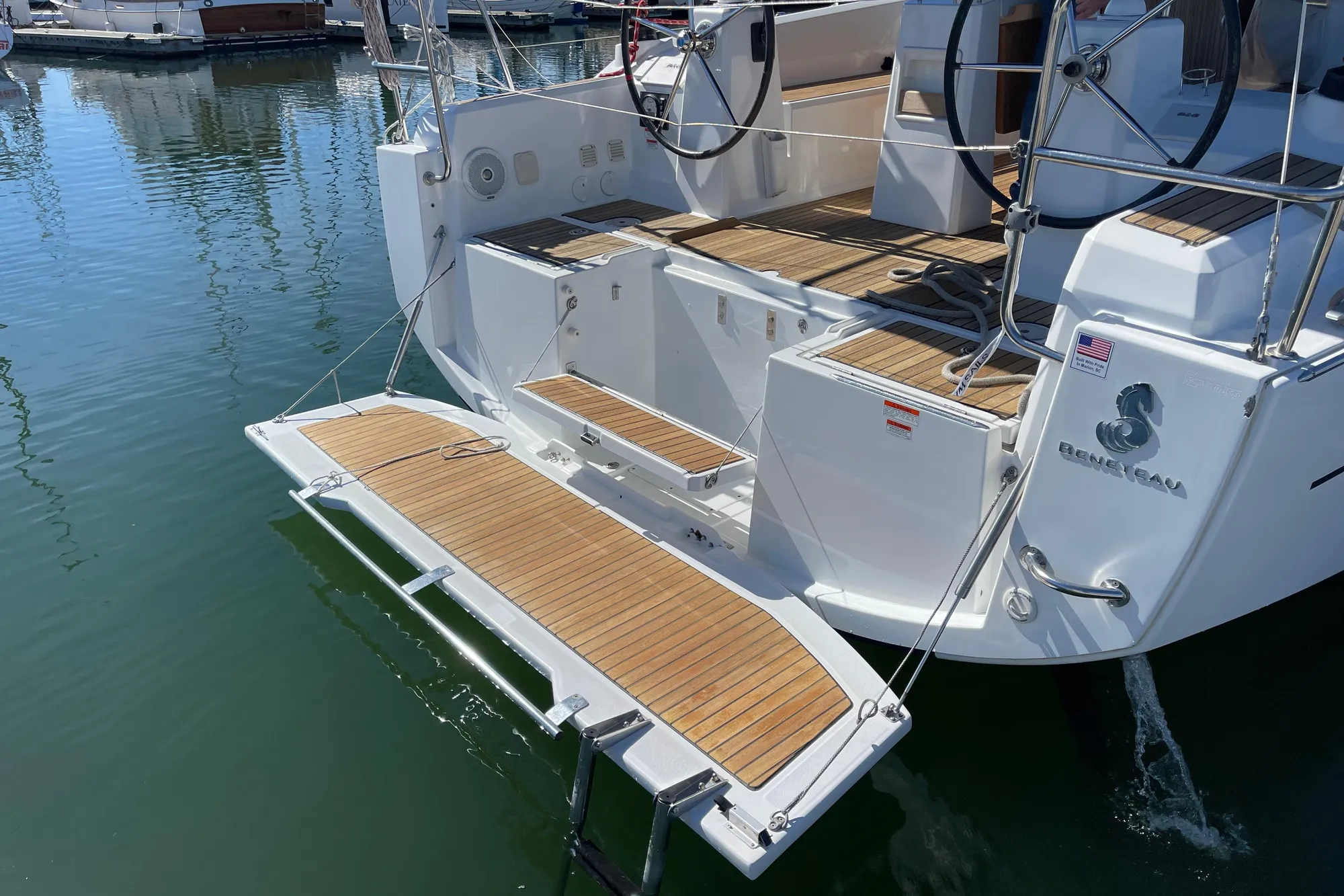 2015 Beneteau First 235 yacht with teak deck and swim platform in marina.