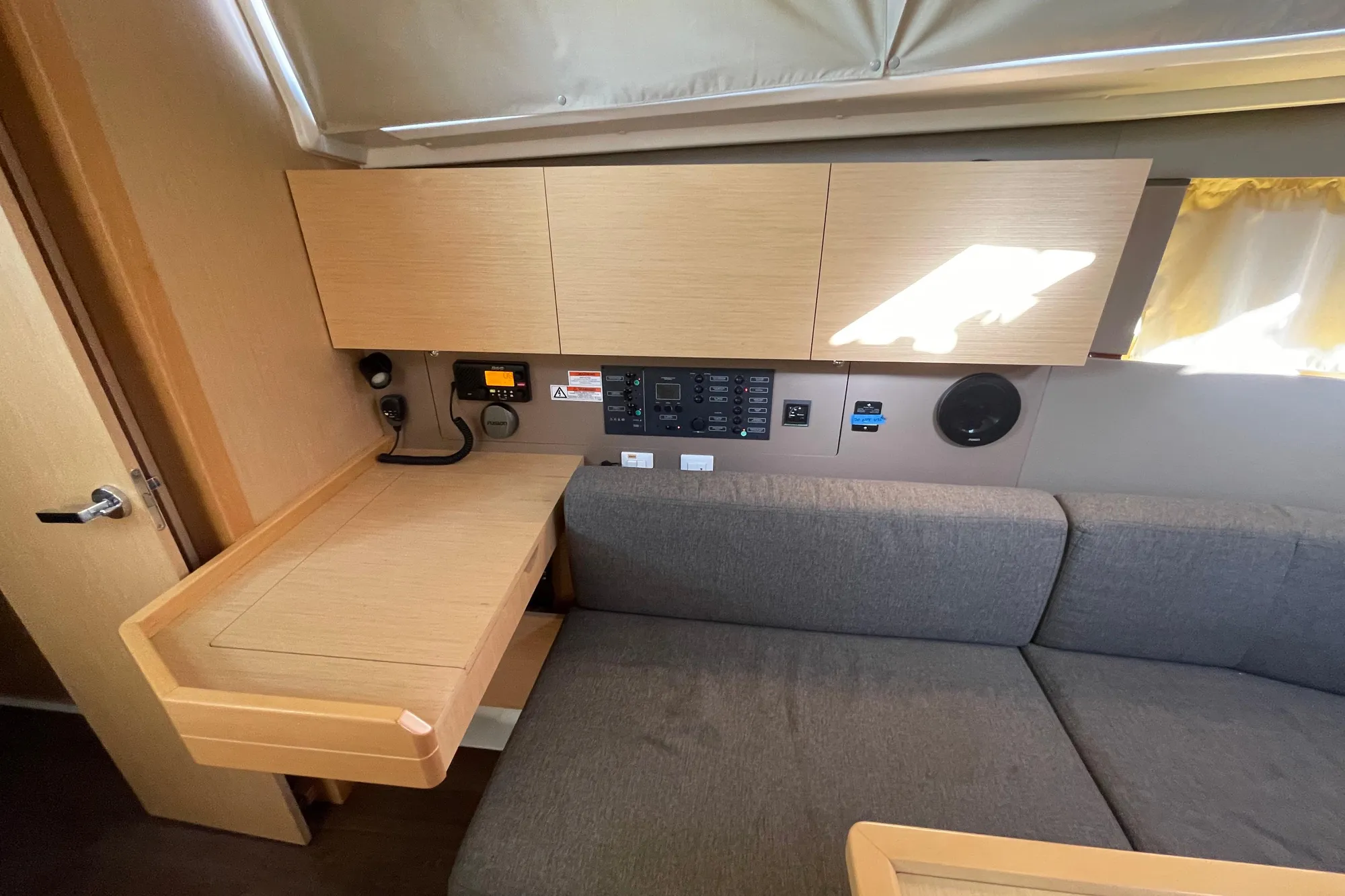 Interior of 2015 Beneteau First 235 sailboat with wooden cabinetry and gray seating.