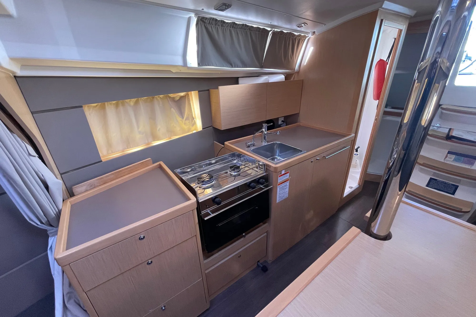 Modern galley kitchen in 2015 Beneteau First 235 sailboat, featuring stove and sink.