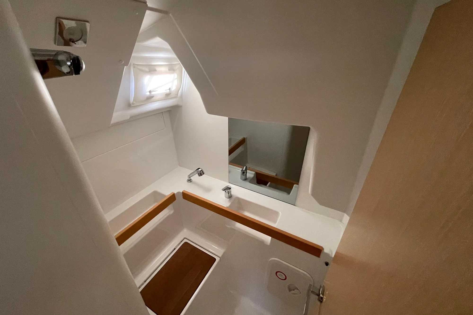 Compact bathroom interior of 2015 Beneteau First 235 sailboat, featuring sink and mirror.