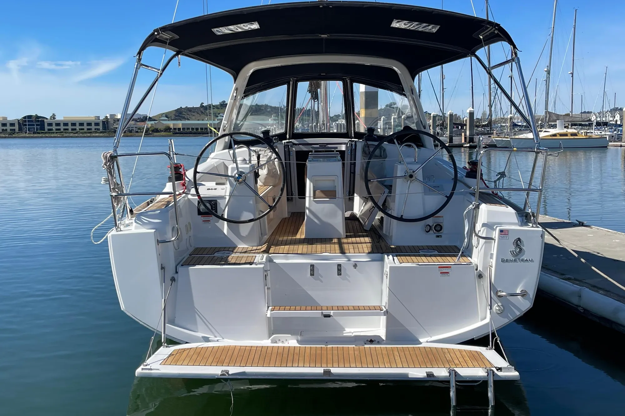 2015 Beneteau First 235 sailboat docked, featuring dual steering wheels and a sleek design.