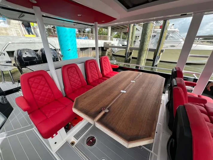  Yacht Photos Pics 2018 Axopar 37 Sun Top with red seating and wooden table in a marina setting.