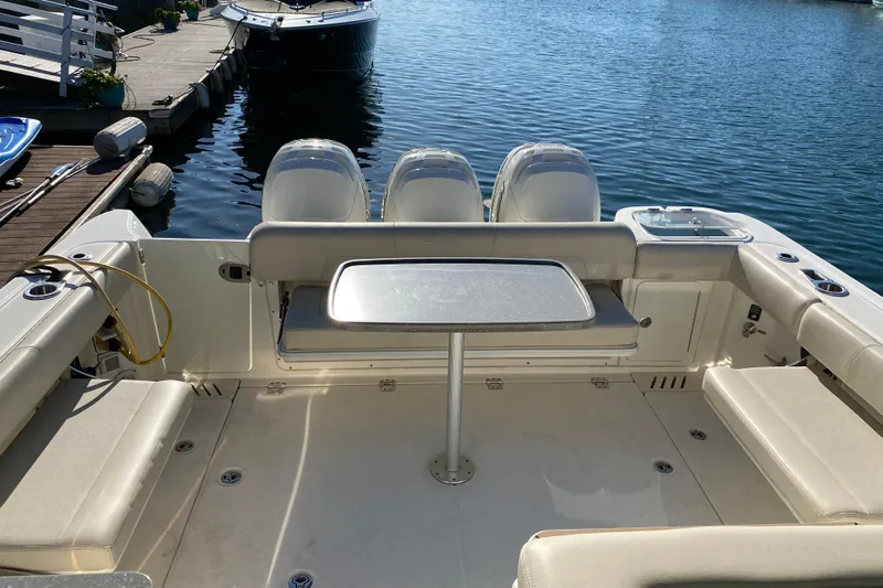 Yacht Photos Pics 2021 Boston Whaler 345 Conquest boat interior with seating and table, docked by the water.