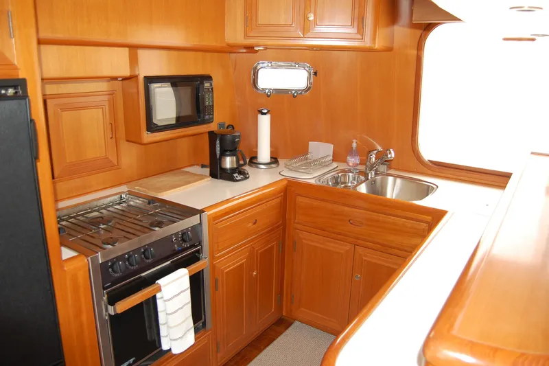 Wandering Bear Yacht Photos Pics 2001 Ocean Alexander Classico yacht kitchen with wood cabinetry, stove, microwave, and sink.
