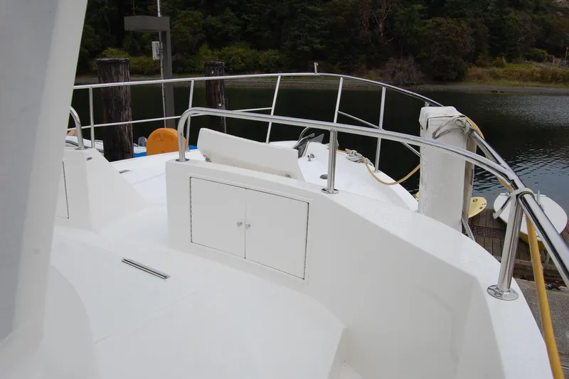 Wandering Bear Yacht Photos Pics Ocean Alexander Classico 2001 yacht deck with railing, docked by a serene waterway.